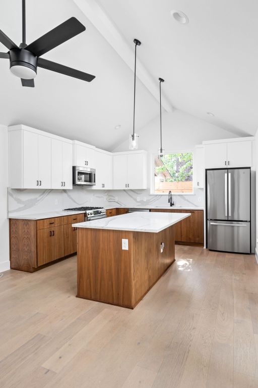 2813 Prado Unit 2, Austin, TX 78702 - kitchen featuring stainless steel appliances, light wood-style floors, a kitchen island, brown cabinets, and white cabinets