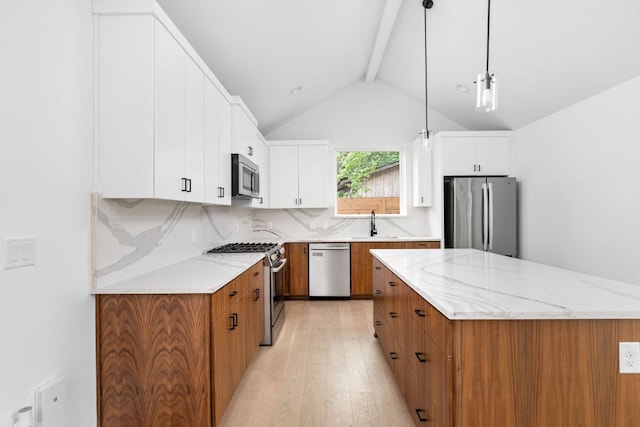 2813 Prado Unit 2, Austin, TX 78702 - kitchen featuring stainless steel appliances, light wood finished floors, a center island, brown cabinets, and decorative light fixtures