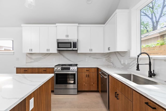 2813 Prado Unit 2, Austin, TX 78702 - kitchen featuring stainless steel appliances, light stone countertops, light wood-type flooring, white cabinets, and brown cabinetry