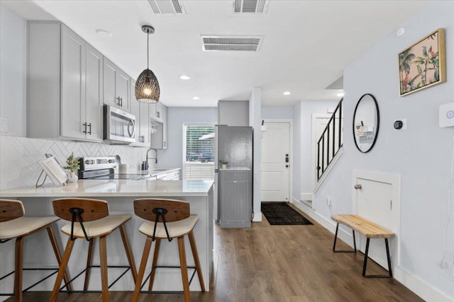 3812 Southway Dr Unit 103, Austin, TX 78704 - kitchen featuring electric range, stainless steel microwave, a peninsula, a kitchen bar, and light countertops