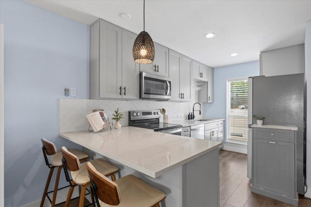 3812 Southway Dr Unit 103, Austin, TX 78704 - kitchen featuring stainless steel appliances, gray cabinetry, a kitchen breakfast bar, backsplash, and recessed lighting