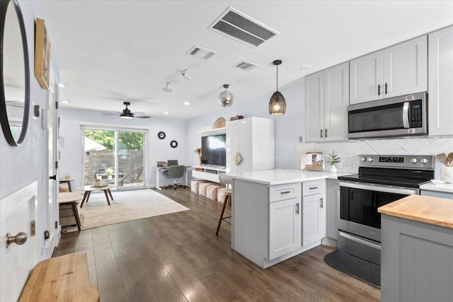 3812 Southway Dr Unit 103, Austin, TX 78704 - kitchen featuring stainless steel appliances, a peninsula, decorative backsplash, dark wood finished floors, and recessed lighting
