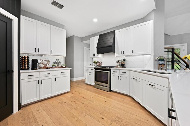 3703 Runnels Ct, Austin, TX 78732 - kitchen featuring custom exhaust hood, stainless steel gas stove, recessed lighting, light wood finished floors, and light countertops