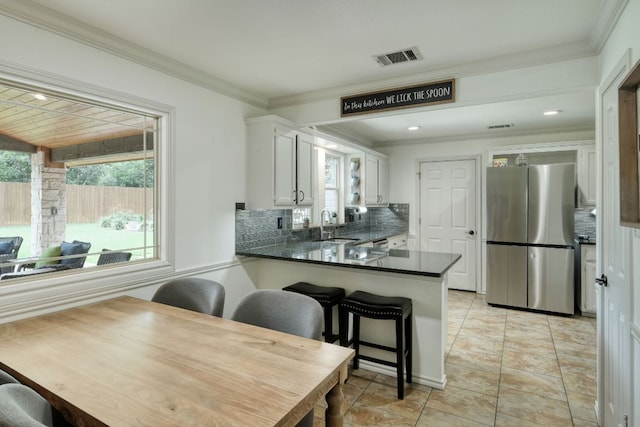 2018 Shadowbrook Cir, Round Rock, TX 78681 - kitchen with freestanding refrigerator, tasteful backsplash, crown molding, dark countertops, and white cabinetry