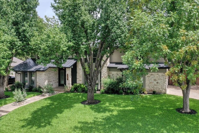 2018 Shadowbrook Cir, Round Rock, TX 78681 - view of front of house with stone siding, a front yard, a standing seam roof, and a metal roof