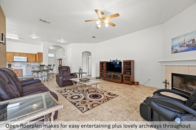 118 Lone Star Blvd, Hutto, TX 78634 - living area featuring arched walkways, ceiling fan, a fireplace, and light tile patterned flooring
