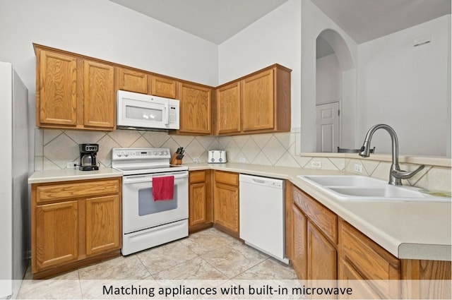 118 Lone Star Blvd, Hutto, TX 78634 - kitchen with white appliances, backsplash, light countertops, and brown cabinetry