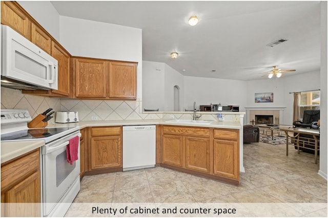118 Lone Star Blvd, Hutto, TX 78634 - kitchen with white appliances, ceiling fan, a peninsula, light countertops, and a tiled fireplace