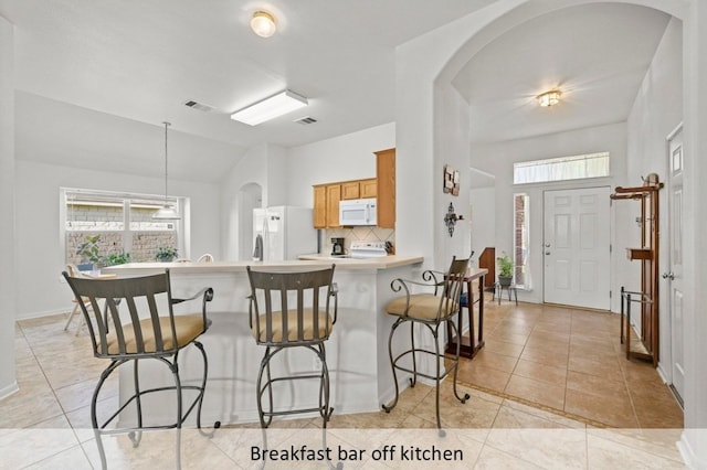 118 Lone Star Blvd, Hutto, TX 78634 - kitchen featuring white appliances, brown cabinets, decorative backsplash, a breakfast bar, and light countertops