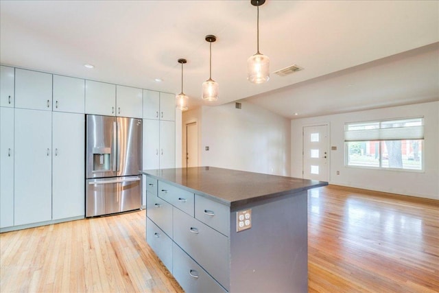 6602 Daugherty St, Austin, TX 78757 - kitchen with stainless steel fridge with ice dispenser, light wood-style flooring, dark countertops, a center island, and hanging light fixtures