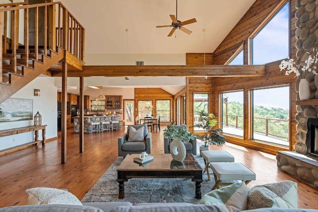 8152 Breeze Way, Jonestown, TX 78645 - living room featuring high vaulted ceiling, hardwood / wood-style flooring, a ceiling fan, stairs, and a stone fireplace
