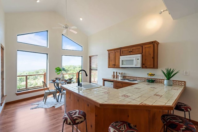 8152 Breeze Way, Jonestown, TX 78645 - kitchen with white appliances, tile countertops, a kitchen breakfast bar, ceiling fan, and wood finished floors