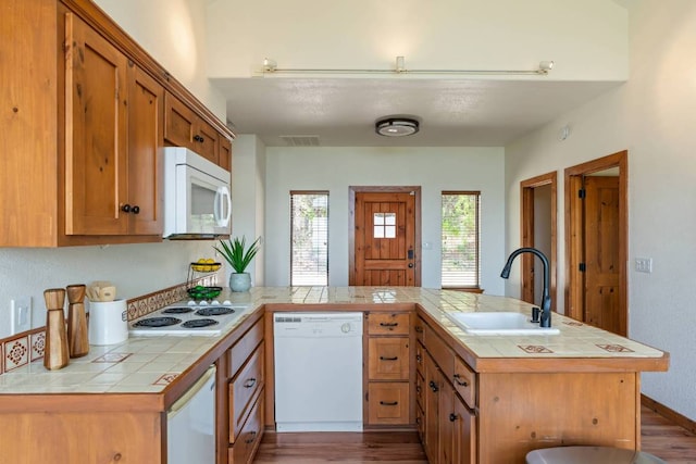 8152 Breeze Way, Jonestown, TX 78645 - kitchen with white appliances, a peninsula, dark wood-style flooring, tile countertops, and brown cabinets
