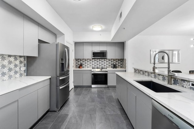54 Rainey St Unit 1018, Austin, TX 78701 - kitchen with gray cabinets, tasteful backsplash, stainless steel appliances, and light stone counters
