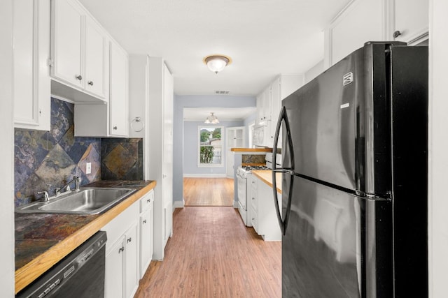 5513 Jim Hogg Ave, Austin, TX 78756 - kitchen with freestanding refrigerator, white range with gas cooktop, black dishwasher, light wood-style floors, and white cabinetry