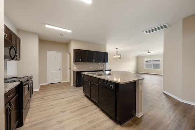 15212 Shell Bark Cv, Austin, TX 78724 - kitchen with black appliances, light wood finished floors, backsplash, light stone countertops, and open floor plan