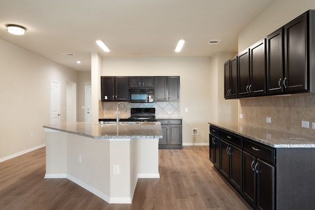 15212 Shell Bark Cv, Austin, TX 78724 - kitchen featuring black appliances, light wood-style flooring, tasteful backsplash, and light stone counters