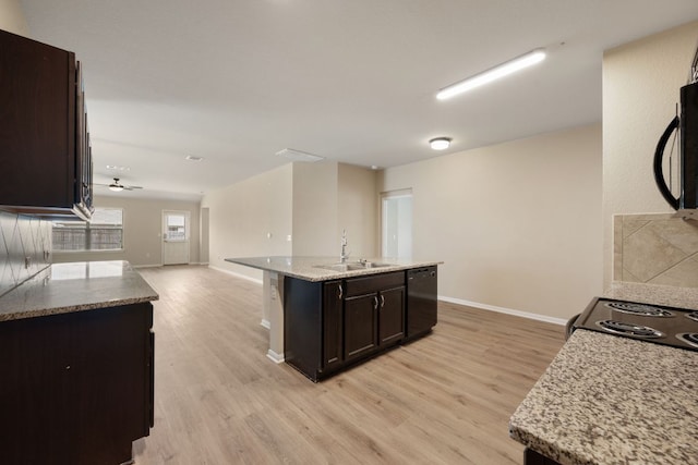 15212 Shell Bark Cv, Austin, TX 78724 - kitchen featuring black appliances, light wood-style floors, open floor plan, an island with sink, and dark brown cabinets