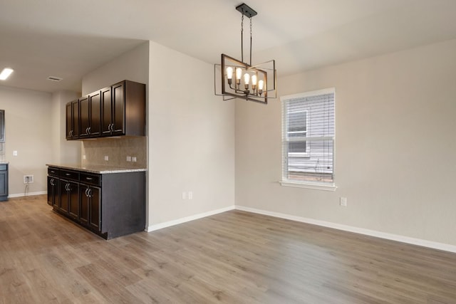 15212 Shell Bark Cv, Austin, TX 78724 - kitchen with light wood finished floors, dark brown cabinetry, a chandelier, and decorative light fixtures