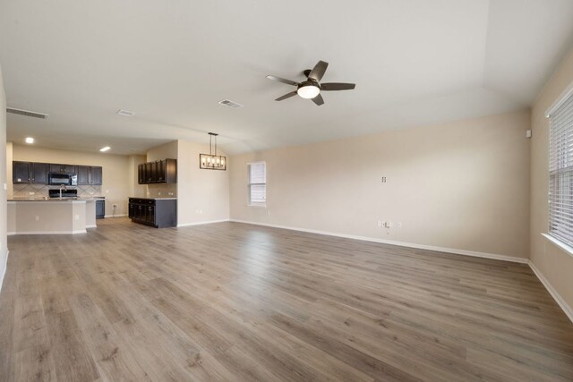 15212 Shell Bark Cv, Austin, TX 78724 - unfurnished living room featuring a ceiling fan, wood finished floors, a chandelier, and recessed lighting