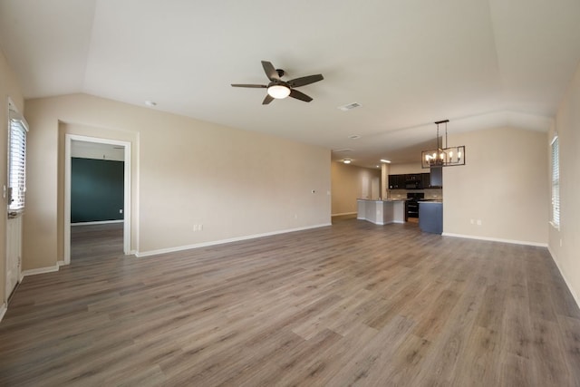 15212 Shell Bark Cv, Austin, TX 78724 - unfurnished living room with lofted ceiling, a chandelier, ceiling fan, plenty of natural light, and wood finished floors
