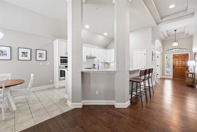 10408 Hansa Dr, Austin, TX 78739 - kitchen with stainless steel appliances, under cabinet range hood, white cabinets, wood finished floors, and light countertops