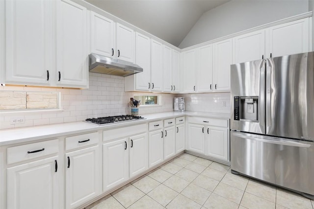 10408 Hansa Dr, Austin, TX 78739 - kitchen featuring appliances with stainless steel finishes, under cabinet range hood, light tile patterned flooring, vaulted ceiling, and decorative backsplash
