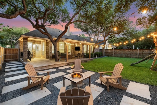 10408 Hansa Dr, Austin, TX 78739 - patio terrace at dusk featuring a fire pit, a wooden deck, a fenced backyard, a playground, and a patio area