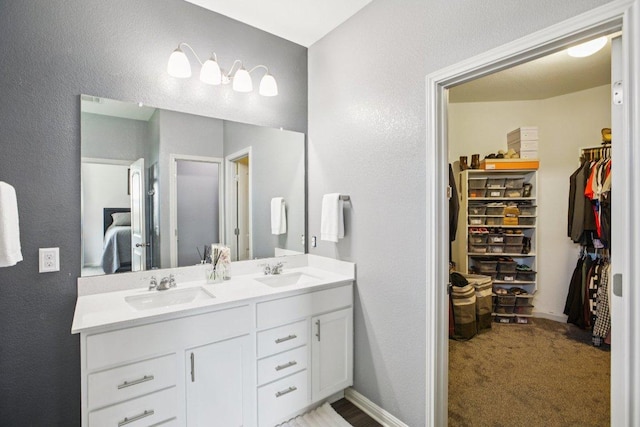 16601 Aventura Ave, Pflugerville, TX 78660 - ensuite bathroom with double vanity, a textured wall, and a walk in closet