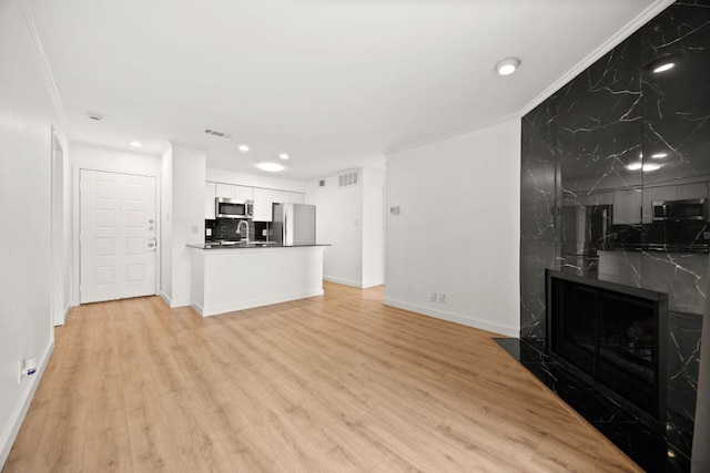 8888 Tallwood Dr Unit 1202, Austin, TX 78759 - unfurnished living room featuring ornamental molding, a fireplace, light wood-style floors, and recessed lighting