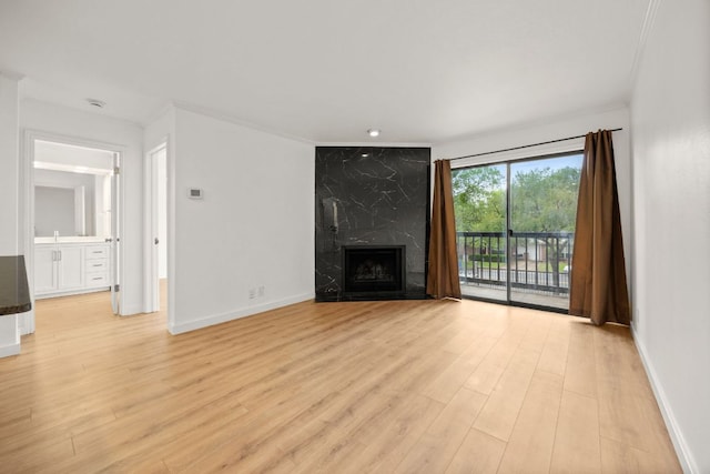 8888 Tallwood Dr Unit 1202, Austin, TX 78759 - unfurnished living room featuring light wood-style flooring, ornamental molding, and a high end fireplace