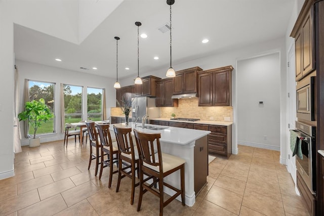 707 Campino Dr, Cedar Park, TX 78613 - kitchen featuring stainless steel appliances, under cabinet range hood, tasteful backsplash, light countertops, and a kitchen breakfast bar