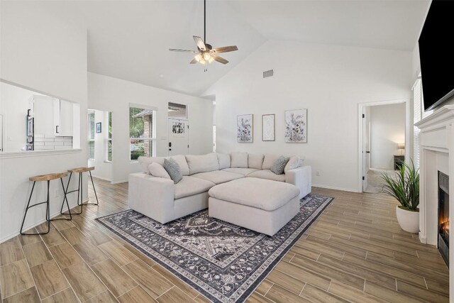 2901 Rochelle Dr, Austin, TX 78748 - living room featuring high vaulted ceiling, a lit fireplace, ceiling fan, and light wood-style flooring