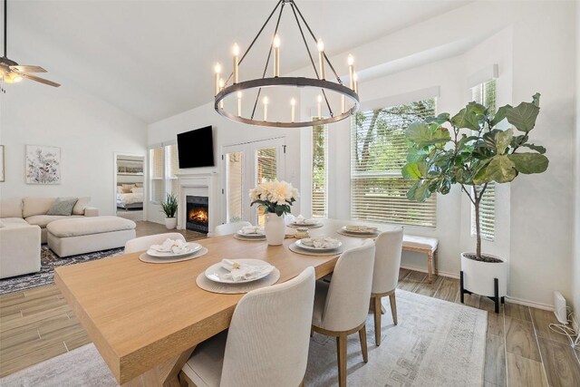2901 Rochelle Dr, Austin, TX 78748 - dining room featuring light wood-type flooring, a warm lit fireplace, a chandelier, high vaulted ceiling, and a ceiling fan