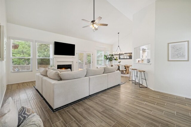 2901 Rochelle Dr, Austin, TX 78748 - living room with wood finished floors, ceiling fan, a lit fireplace, high vaulted ceiling, and a chandelier
