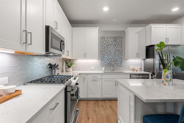 1125 Tillery St Unit 1A, Austin, TX 78702 - kitchen featuring appliances with stainless steel finishes, light wood-type flooring, backsplash, white cabinetry, and recessed lighting