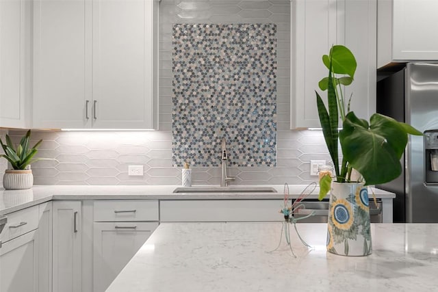 1125 Tillery St Unit 1A, Austin, TX 78702 - kitchen featuring stainless steel fridge, white cabinets, decorative backsplash, and light stone countertops