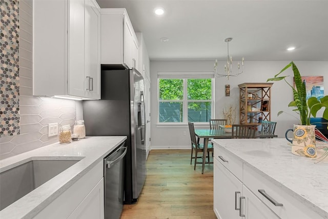 1125 Tillery St Unit 1A, Austin, TX 78702 - kitchen with stainless steel dishwasher, a chandelier, light wood-style flooring, white cabinetry, and backsplash