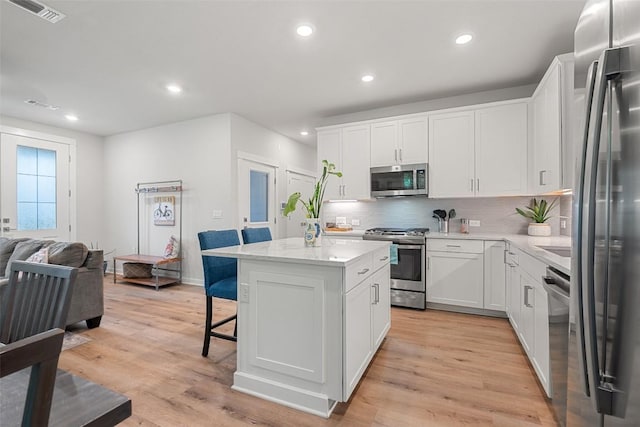 1125 Tillery St Unit 1A, Austin, TX 78702 - kitchen with appliances with stainless steel finishes, backsplash, a breakfast bar, open floor plan, and a kitchen island