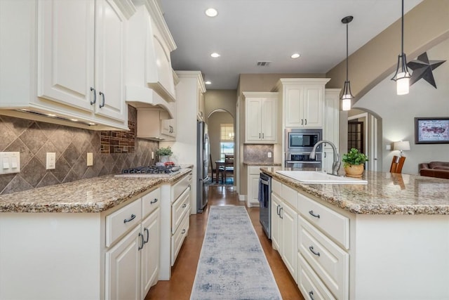 9769 Fm 1361, Snook, TX 77879 - kitchen featuring arched walkways, stainless steel appliances, an island with sink, white cabinets, and decorative backsplash