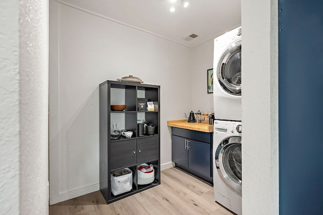 6101 Bridlington Cir, Austin, TX 78745 - washroom with stacked washer / dryer, cabinet space, and light wood-style floors