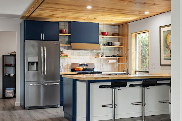 6101 Bridlington Cir, Austin, TX 78745 - kitchen featuring appliances with stainless steel finishes, wooden counters, open shelves, blue cabinetry, and range hood