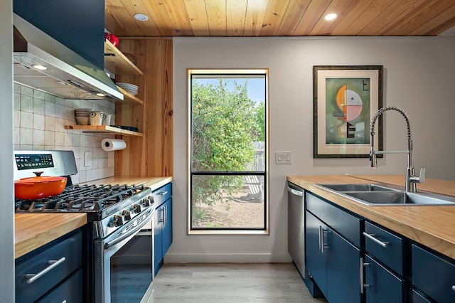 6101 Bridlington Cir, Austin, TX 78745 - kitchen with stainless steel appliances, blue cabinets, butcher block counters, open shelves, and recessed lighting