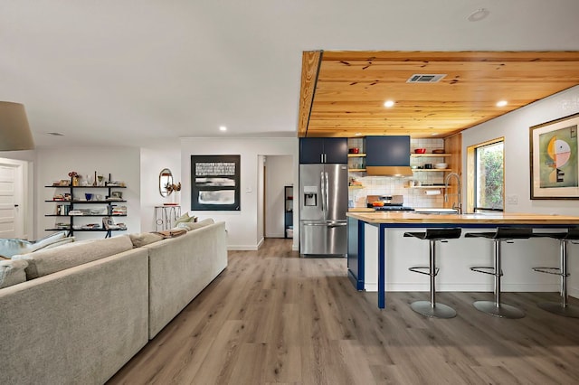 6101 Bridlington Cir, Austin, TX 78745 - kitchen featuring appliances with stainless steel finishes, open shelves, a breakfast bar, wood counters, and light wood finished floors