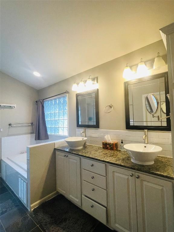 2003 Woodmont Ave, Austin, TX 78703 - bathroom with double vanity, vaulted ceiling, a garden tub, and tile patterned floors