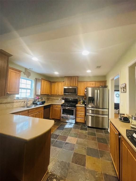 2003 Woodmont Ave, Austin, TX 78703 - kitchen with appliances with stainless steel finishes, backsplash, light countertops, recessed lighting, and dark stone finish floors