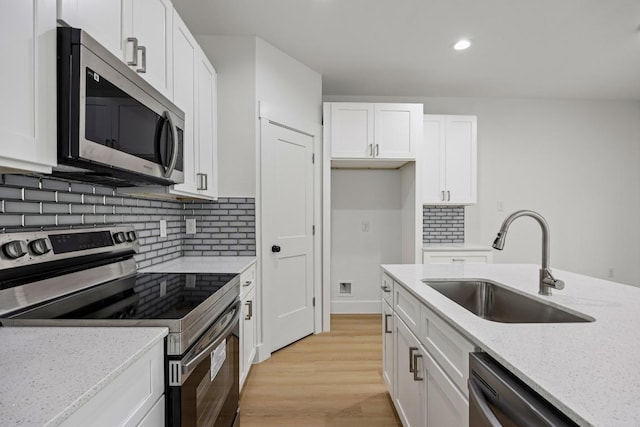 161 Honopu Dr, Bastrop, TX 78602 - kitchen featuring appliances with stainless steel finishes, white cabinets, light wood-style flooring, light stone counters, and tasteful backsplash