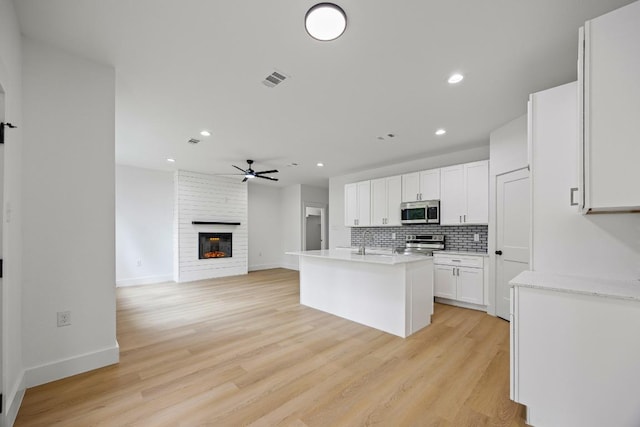 161 Honopu Dr, Bastrop, TX 78602 - kitchen with appliances with stainless steel finishes, ceiling fan, tasteful backsplash, light countertops, and white cabinetry
