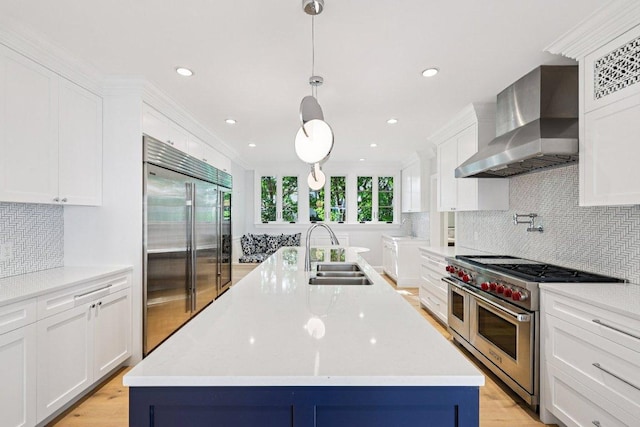 5 Green Ln, Austin, TX 78703 - kitchen featuring wall chimney range hood, high end appliances, white cabinets, an island with sink, and tasteful backsplash