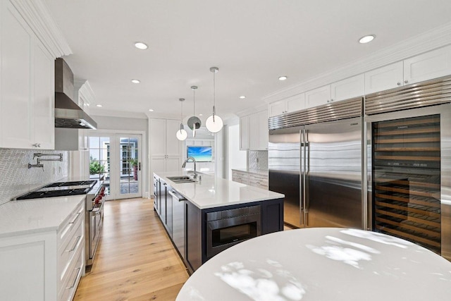 5 Green Ln, Austin, TX 78703 - kitchen with built in appliances, wall chimney exhaust hood, beverage cooler, light countertops, and white cabinets